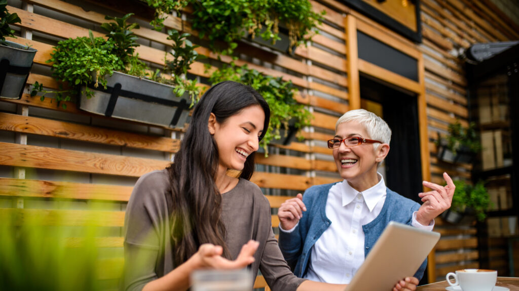 Two happy smiling women using digital tablet at the bar