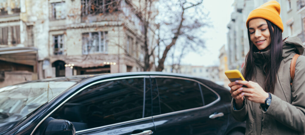 Woman on cell phone next to car