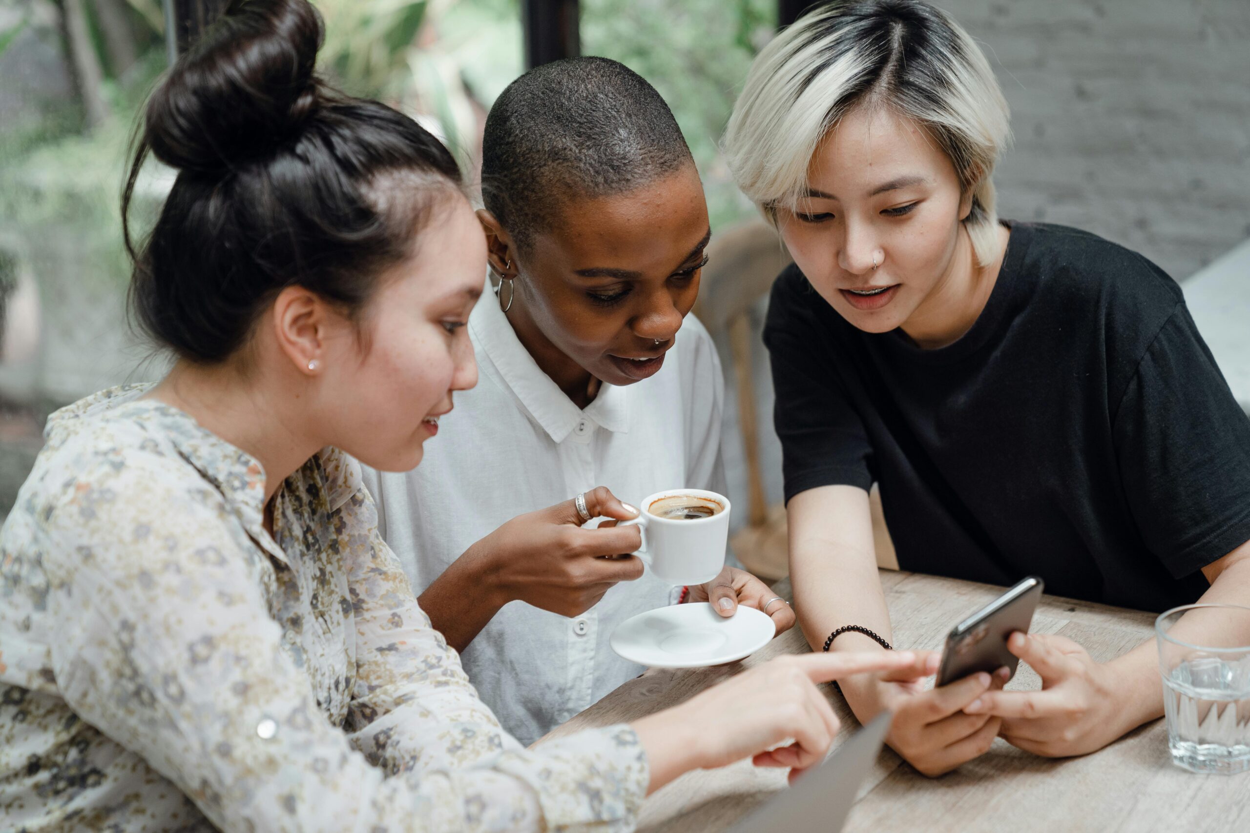 Teens together at cafe looking at a phone.