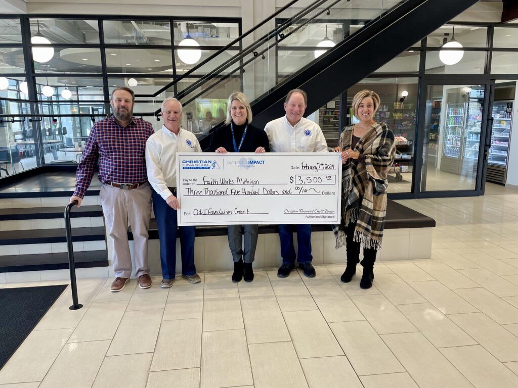 Faith Works representatives standing with large check